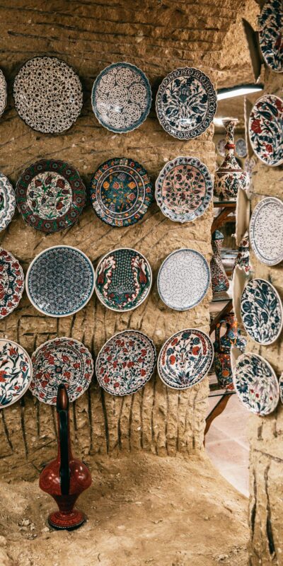 Many oriental plates with different ornaments decorating rough stone walls in daytime in Morocco